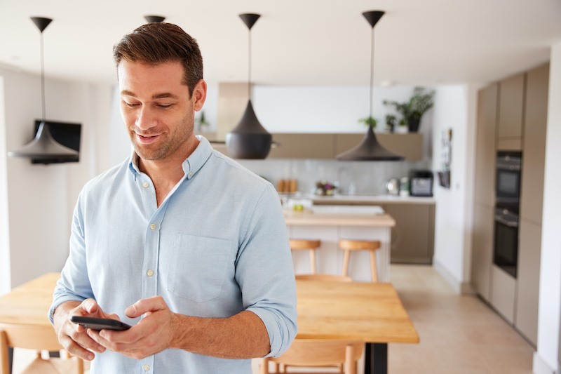 man managing smart thermostat from his mobile phone